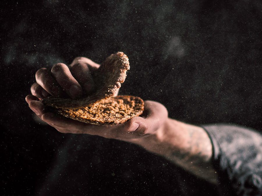 Hands breaking rye bread.